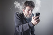 © Teodor Lazarev - Young man insanely furious yelling at his phone, giving off steam and smoke