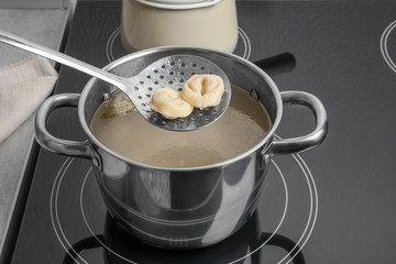 Wall Mural - Cooked dumplings on skimmer over saucepan