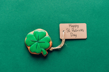 top view of icing cookie in shape of shamrock on green, st patricks day concept