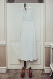 Fototapeta  - Suknia ślubna wisząca na białej szafie oraz buty.