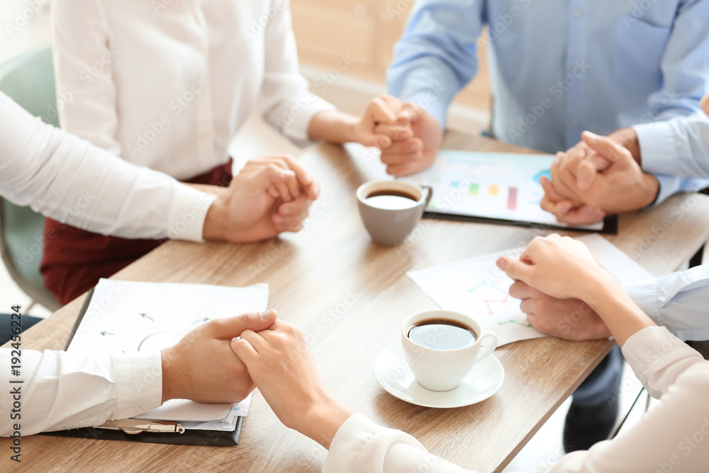Young people in office wear holding hands indoors. Unity concept