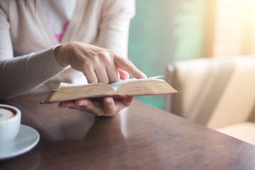 Sticker - woman hands on bible. she is reading and praying over bible over wooden table