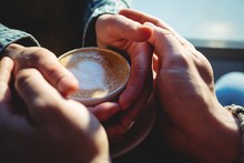 Close-up Of Man And Woman Holding Coffee Cup At Cafeteria