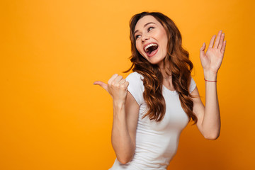 Poster - Laughing brunette woman in t-shirt looking and pointing away