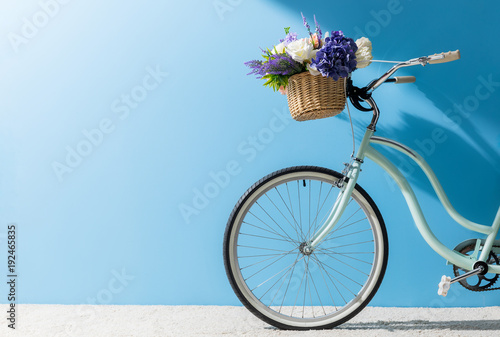 Dekoracja na wymiar  przednie-kolo-roweru-z-kwiatami-w-koszu-przed-niebieska-sciana