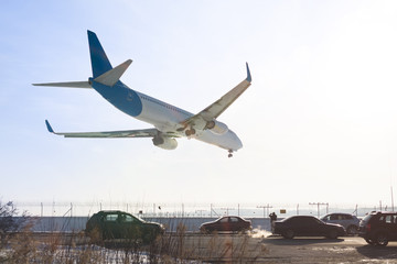 Tail view of landing airplane. Aircraft flying over highway.  Road with high traffic near airport runway. Type of transport comparison.  Travel concept