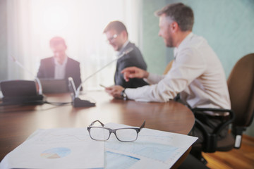 Wall Mural - financial chart near dollars seen by unfocused glasses ( colleagues meeting to discuss their future financial plans only silhouettes being viewed )
