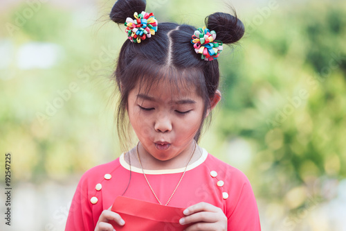 Cute Asian Child Girl Opening And Looking Money In Red Envelope