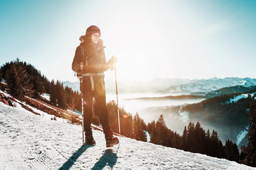 Wall Mural - Woman hiking along a snowy mountain road in winter