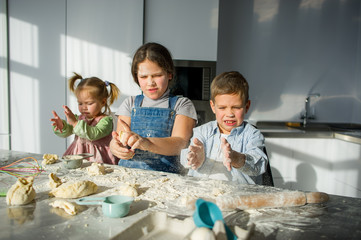 Wall Mural - Three children prepare something from the dough.