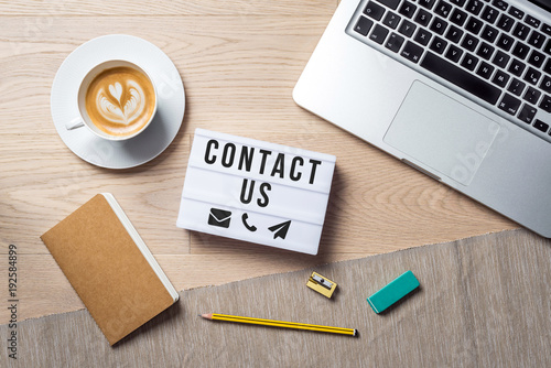 Fotografía Contact us writing in lightbox lying on desk as flatlay