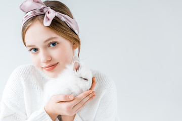 adorable child holding furry white rabbit and looking at camera isolated on white