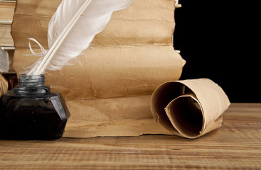 old paper and inkwell with a feather on black background