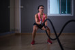 © ibravery - Asia women exercising with battle ropes at gym.