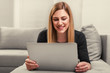 © Denis Rozhnovsky - Attractive woman using a laptop while lying on the couch at home.