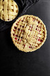 © The Picture Pantry - Pie crust design ideas - various ways of pie decoration with lattice and leaves. Apple, strawberry and raspberry pies uncooked on black table.