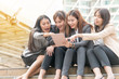 © kaew6566 - Group of businesswoman sitting in the shade on the stairs,looking at digital tablet in a modern city. Beautiful young woman wearing the business suit using tablet and laughing happily.