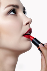 Wall Mural - Portrait of young brunette woman. Girl with lipstick in hand. Female lips beauty makeup concept