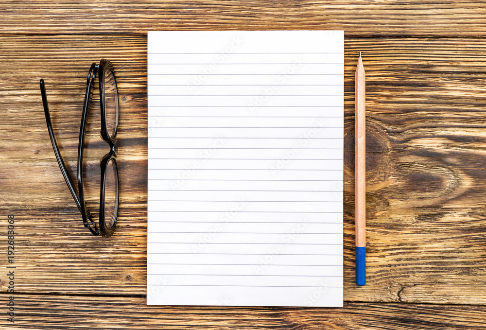 Opened blank notepad with pencil and eyeglasses. Top view. - obrazy, fototapety, plakaty 