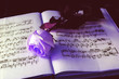 The withering rose lies on the ancient book with notes
