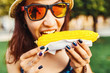 © EdNurg - woman eating a delicious tasty corn in city park