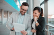 © bnenin - Cheerful business people discussing documents in office hall.