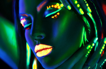 Wall Mural - Fashion model woman in neon light. Portrait of beautiful model girl with colorful fluorescent makeup