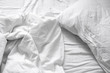 Top view. Close up unmade white bedding sheets and pillow, Messy bed after night sleep concept. textile background. illustration of a romantic date at a hotel, cheating