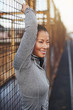 © Flamingo Images - Fit young Asian woman standing against a mesh wall outdoors