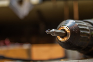 A screwdriver with a bit set on a dark table in the workshop