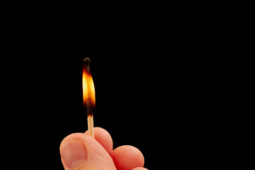 Matchstick in hand isolated on black background