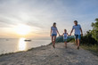 © familylifestyle - Family mom, dad and son walking on a mountain with seascape at sunset. Front view.