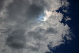 Fototapeta  - Ciężkie bure chmury zasnuwają niebo, po prawe skraj ciemnoniebieskiego nieba, przez chmury przebija odrobina słonecznego światła i błękitu nieba