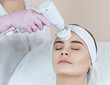 The cosmetologist makes the apparatus  procedure of Hardware face cleaning with a soft rotating brush of a beautiful, young woman in a beauty salon. Cosmetology and professional skin care.