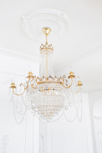 Expensive Interior. Large Electric Chandelier Made Of Transparent Glass Beads. White Ceiling Decorated With Stucco Molding. White Patterned. Mouldings Element From Gypsum.