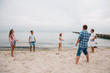 © Maksym Azovtsev - Group of young attractive friends playing frisbee on the beach, by the sea, spending weekend with pleasure.