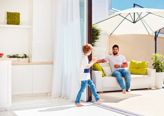 Wall Mural - happy family relaxing on rooftop patio with open space kitchen at warm summer day