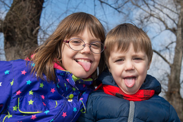 a girl and boy with a sticking out tongue in nature