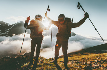 Happy travel couple man and woman on mountain summit love and adventure hiking Lifestyle wanderlust concept sunset light.