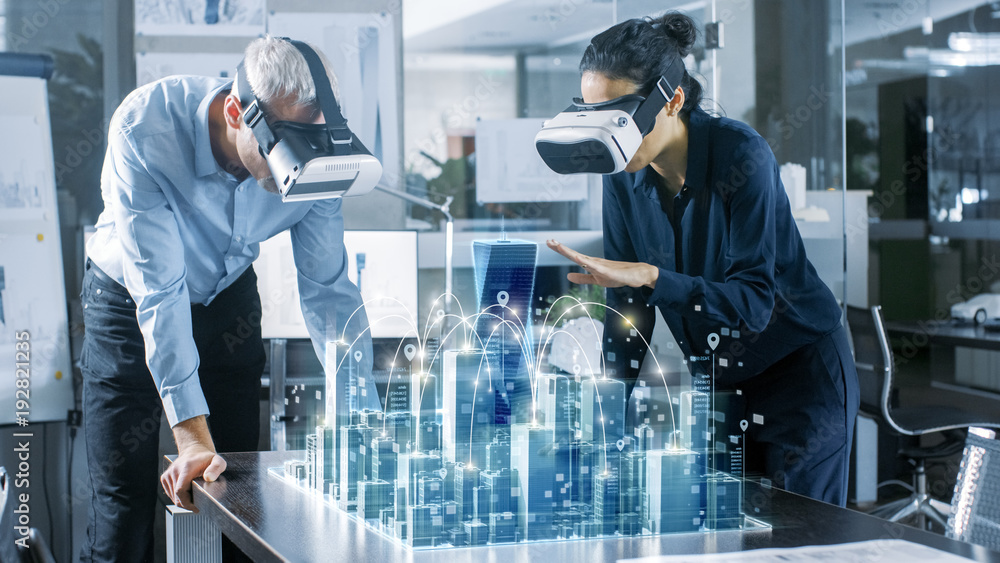 Male and Female Architects Wearing  Augmented Reality Headsets Work with 3D City Model. High Tech Office Professional People Use Virtual Reality Modeling Software Application. - obrazy, fototapety, plakaty 