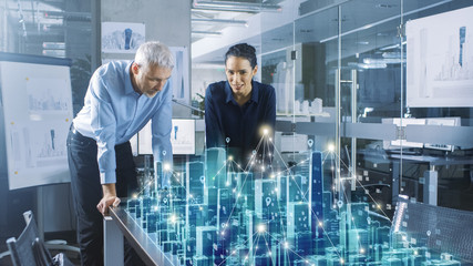 Male and Female Architects Work with Holographic Augmented Reality 3D City Model. Technologically Advanced Office Professional People Use Virtual Reality Modeling Software Application.