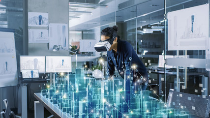 professional female architect wearing makes gestures with augmented reality headset, shows statistic