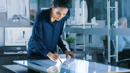 Sticker - Talented Young Female Architectural Designer Draws Building Concept on a Graphics Tablet Display. Clean Minimalistic Office, Concrete Walls Covered by Blueprints.