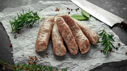 Wall Mural - Freshly made raw breed butchers sausages in skins with herbs on crumpled paper.