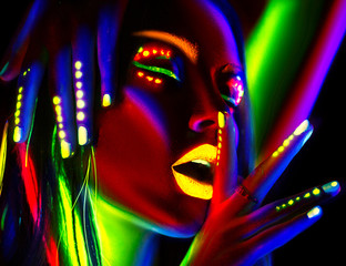 Wall Mural - Fashion model woman in neon light. Portrait of beautiful model girl with colorful fluorescent makeup