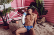 © kanashkin - Sexy african american man in shorts sitting on the beach and holding a life buoy.