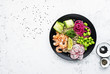 Fresh seafood recipe. Shrimp poke bowl with fresh prawn, brown rice, cucumber, pickled sweet onion, radish, soy beans edamame portioned with black and white sesame. Food concept poke bowl. Top view