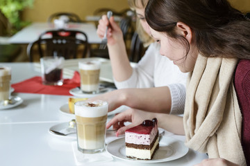 Two friends communicate with food, drink coffee and eat cake.