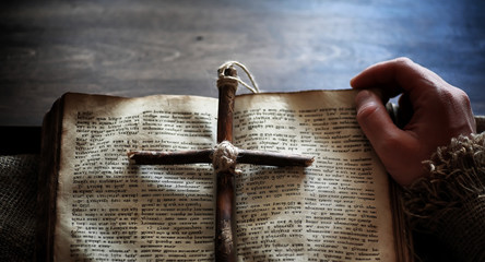 Religious old book on a wooden table. A religious cross tied wit