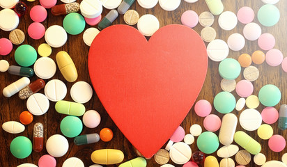 Drugs and coins in a glass jar on a wooden floor. Pocket savings